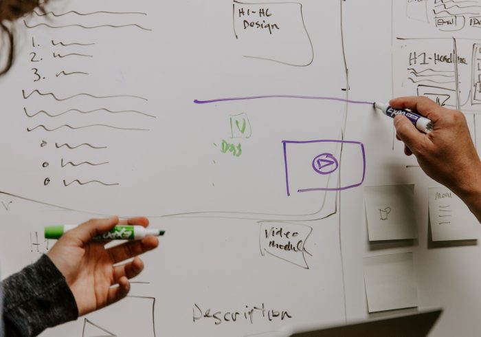 two people drawing on whiteboard