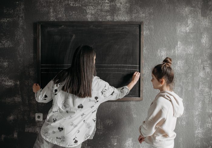Teacher Writing on a Blackboard Beside a Student