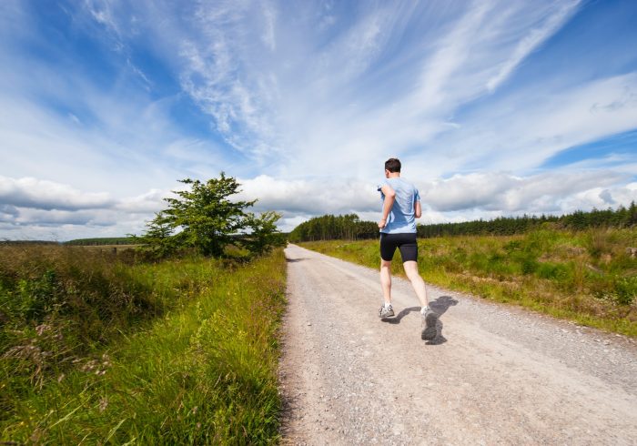 man running on road near grass field